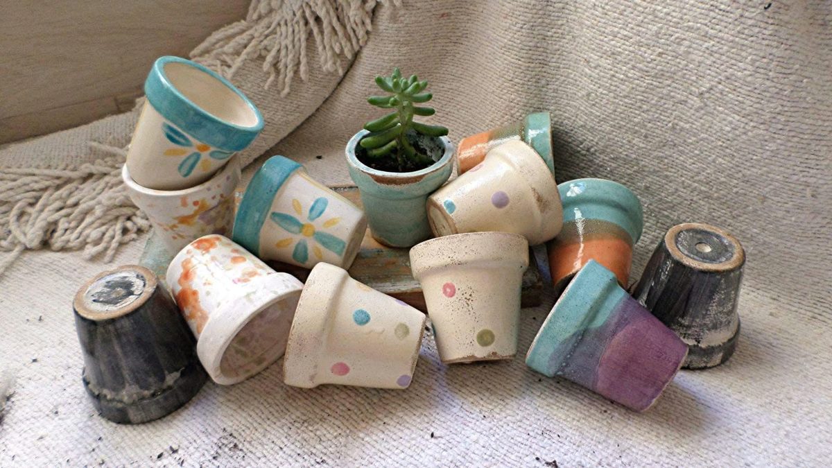 Macetitas de cerámica pintadas con lunares, flores y bordes turquesa, una con una suculenta