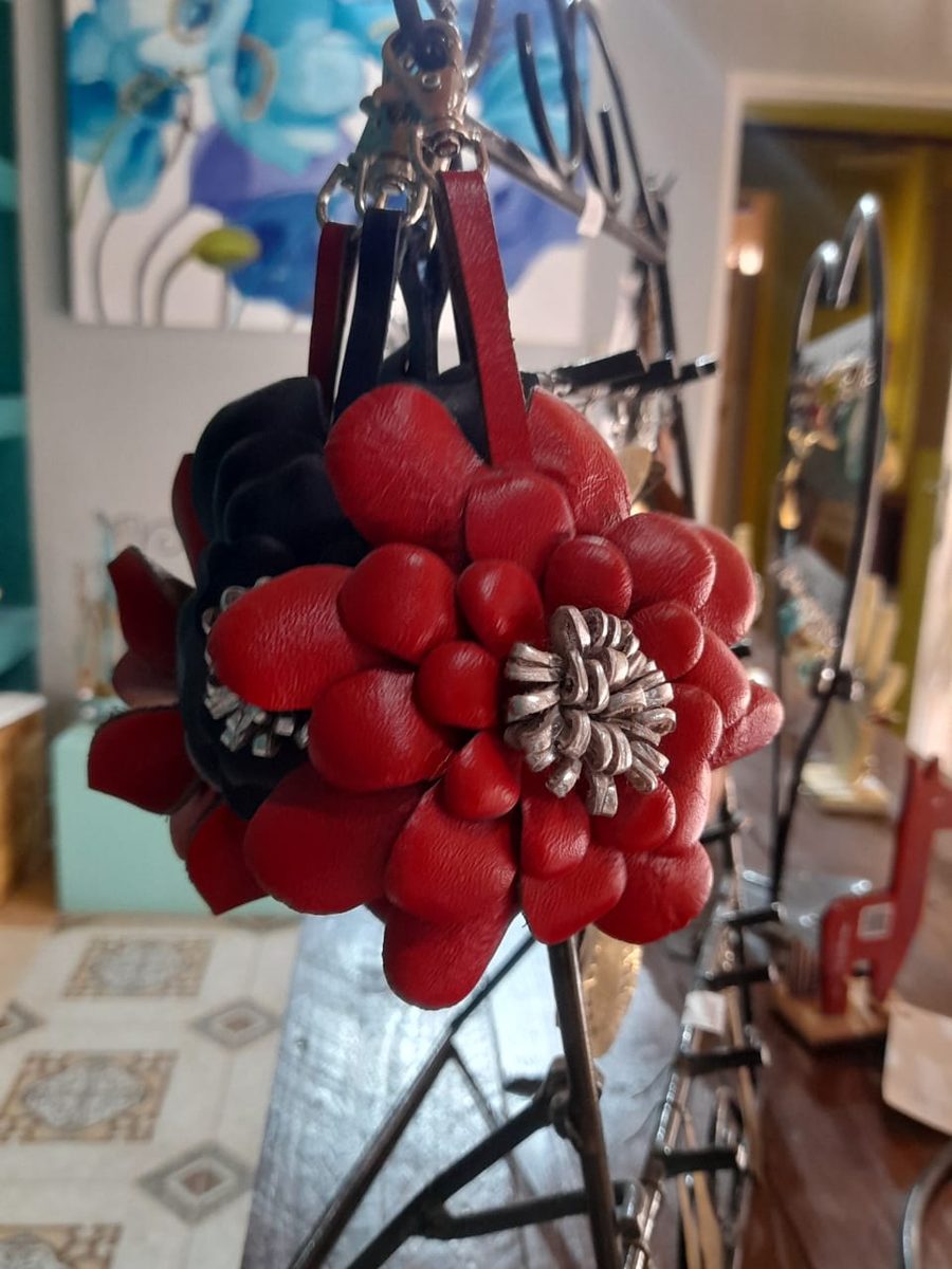 Flor de cuero rojo con centro metálico, colgada de un soporte de hierro